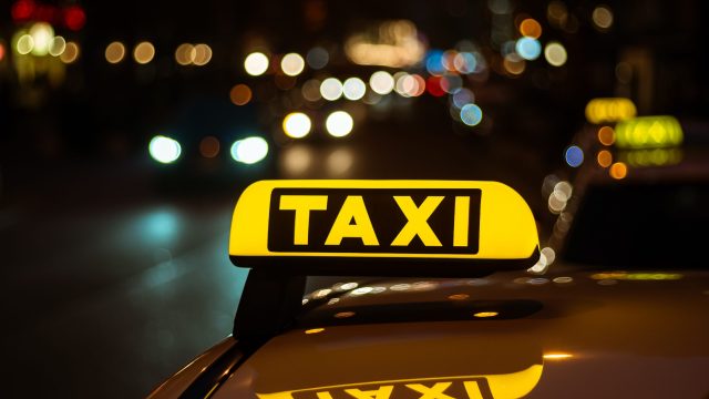 yellow-black-sign-taxi-placed-top-car-night-scaled-1